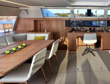Le cockpit se prolonge à l'intérieur par un salon sur tribord et une salle à manger sur bâbord. Une table à cartes fait la jonction entre les deux espaces du carré, adossé à la cloison transversale. Nautisme Article