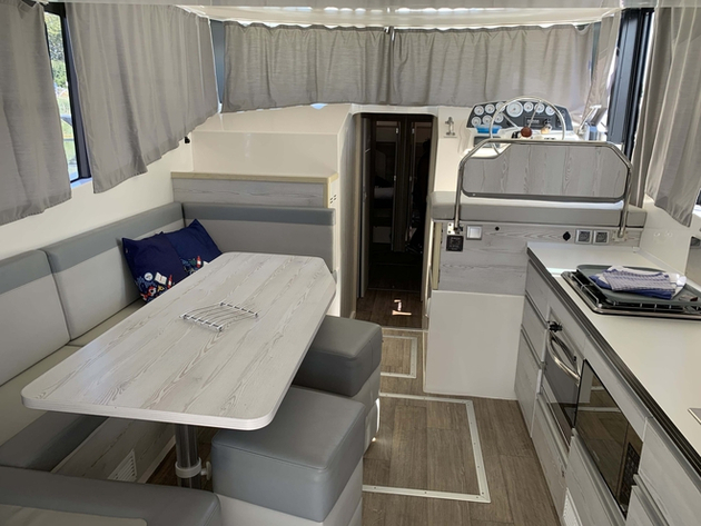 Cuisine équipée, table avec banquette et poste de pilotage avant d'accéder aux cabines. Nautisme Article