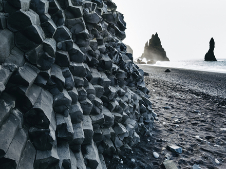 D'imposantes falaises de basalte colonnaire s'élèvent sur le sable sombre et forment une toile de fond naturelle époustouflante. D'imposantes falaises de basalte colonnaire s'élèvent sur le sable sombre et forment une toile de fond naturelle époustouflante.