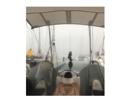 Sous la pluie de décembre en Martinique. On aperçoit la latte jonc de la chute dans son gousset reprise sur les deux tubes en aluminium fichés dans des portes cannes fixés au balcon arrière Nautisme Article
