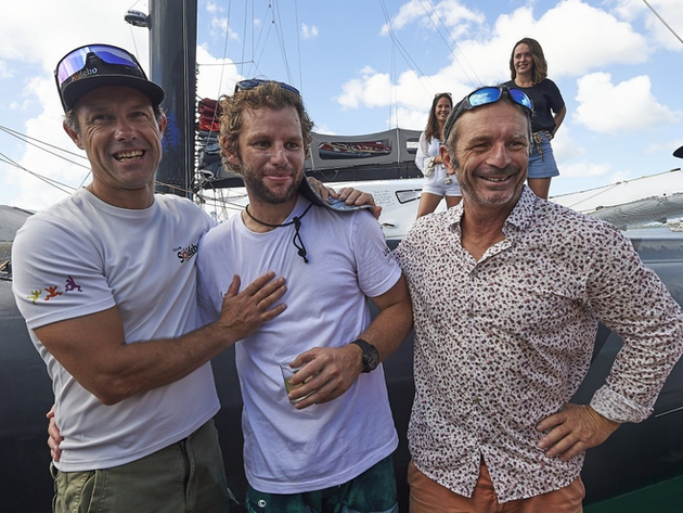 Athur Le Vaillant entouré à son arrivée à Pointe à Pitre des deux précédents skippers de son trimaran Mieux, Thomas Coville et Yves Le Blevec Nautisme Article